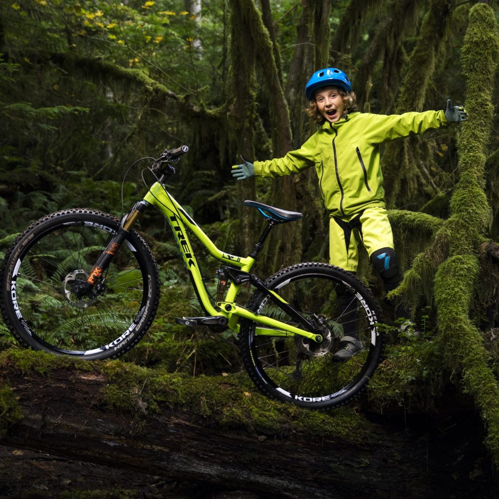 Bike Online Bub in grellgelbem Overall genießt mit seinem Bike den dichten Wald