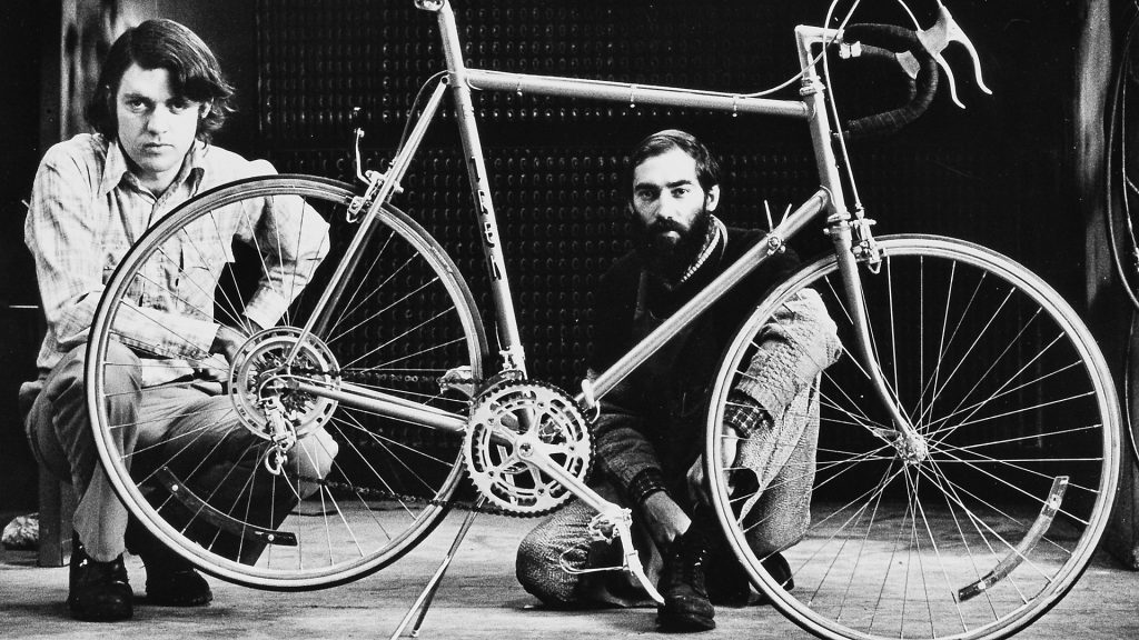 Klassische Aufnahme zweier Mitarbeiter des Fahrradproduzenten Trek vor einem alten Fahrrad in einer Werkstatt